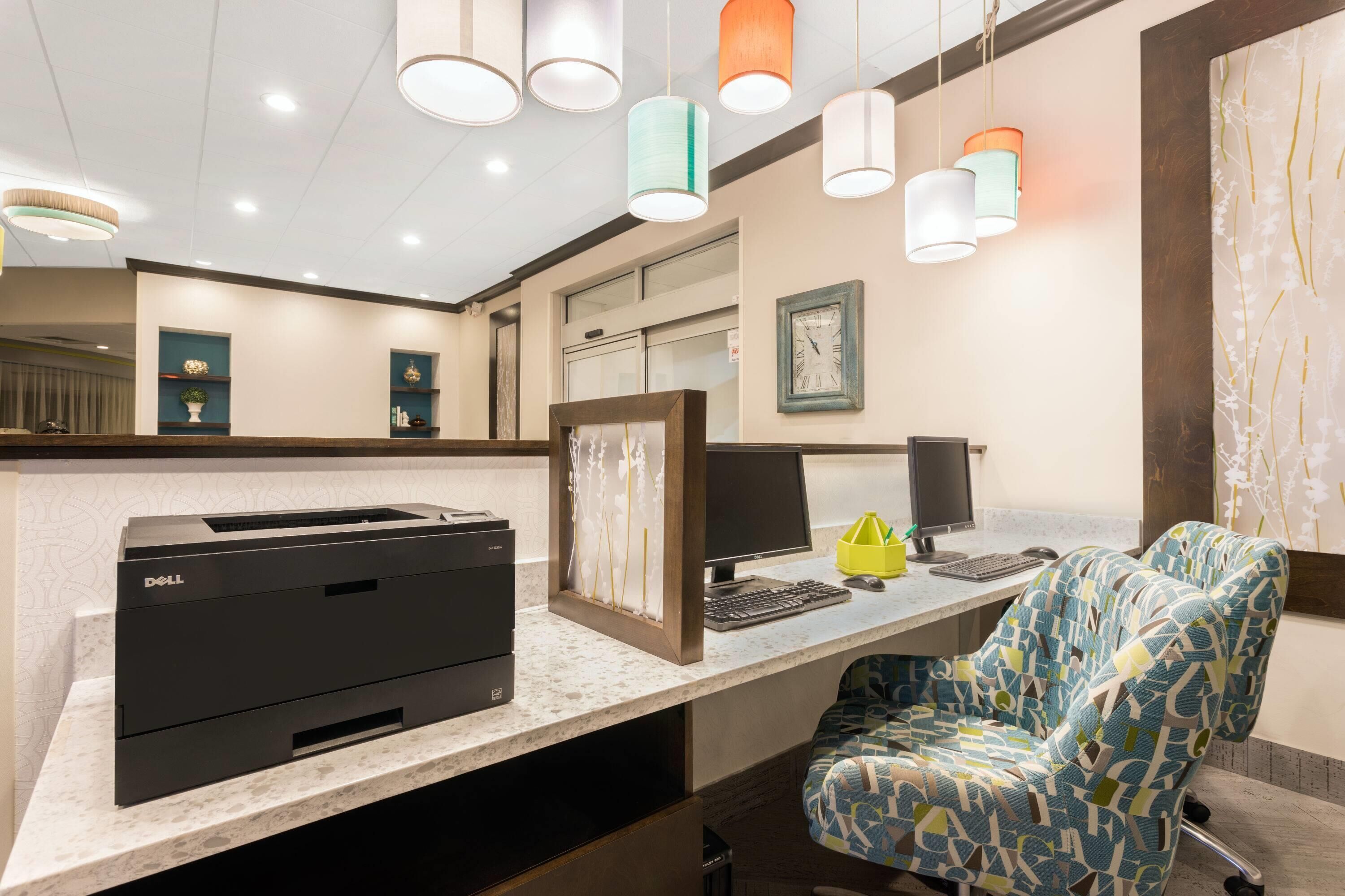 A hotel reception desk with a printer, computer, and seating area.