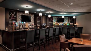 A bar area with a long counter, multiple bar stools, and a television mounted on the wall. - Delta Hotels by Marriott Sault Ste. Marie Waterfront (Sault Ste. Marie)