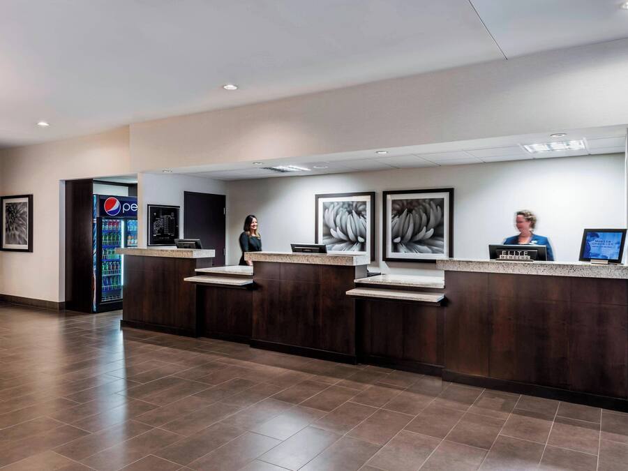 Un área de recepción con un mostrador de madera oscura, un refrigerador de Pepsi y obras de arte enmarcadas en la pared.