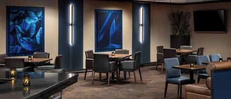 A hotel lobby with a bar area, seating arrangements, and large wall art.