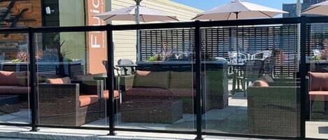 An outdoor seating area with glass partitions, outdoor furniture, and umbrellas.