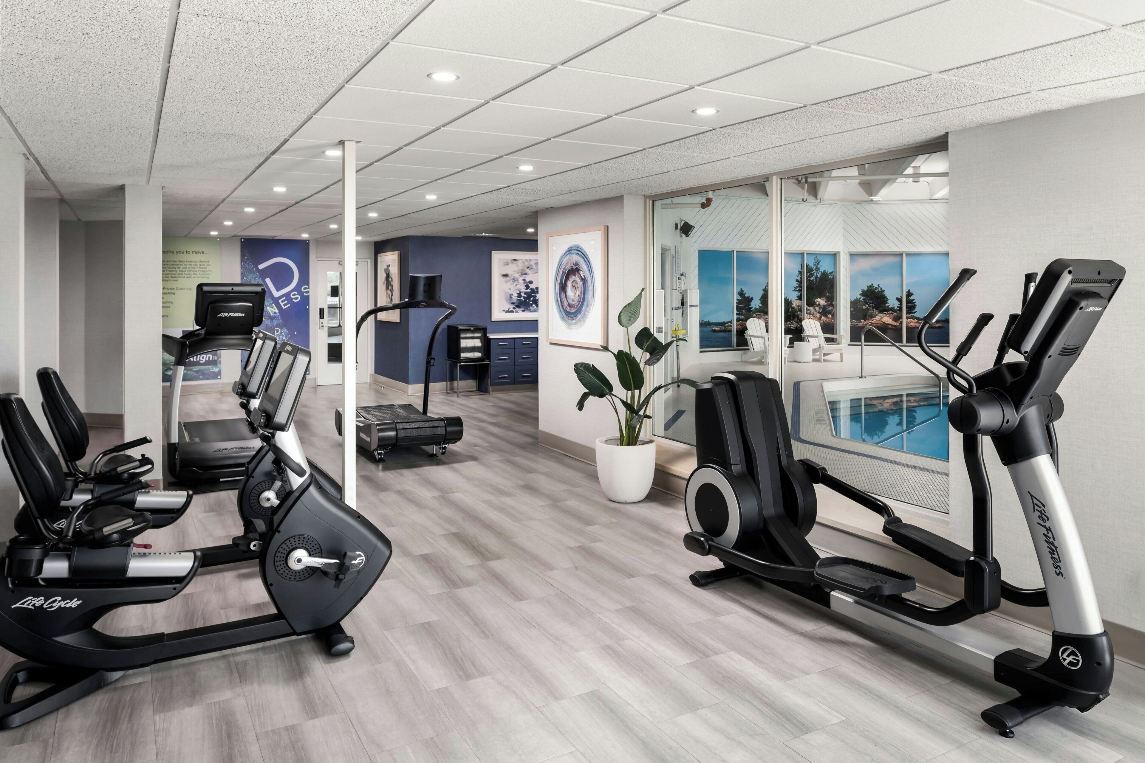 Et fitnessrum med træningsmaskiner, løbebånd og en væg med et naturskønt udsyn.