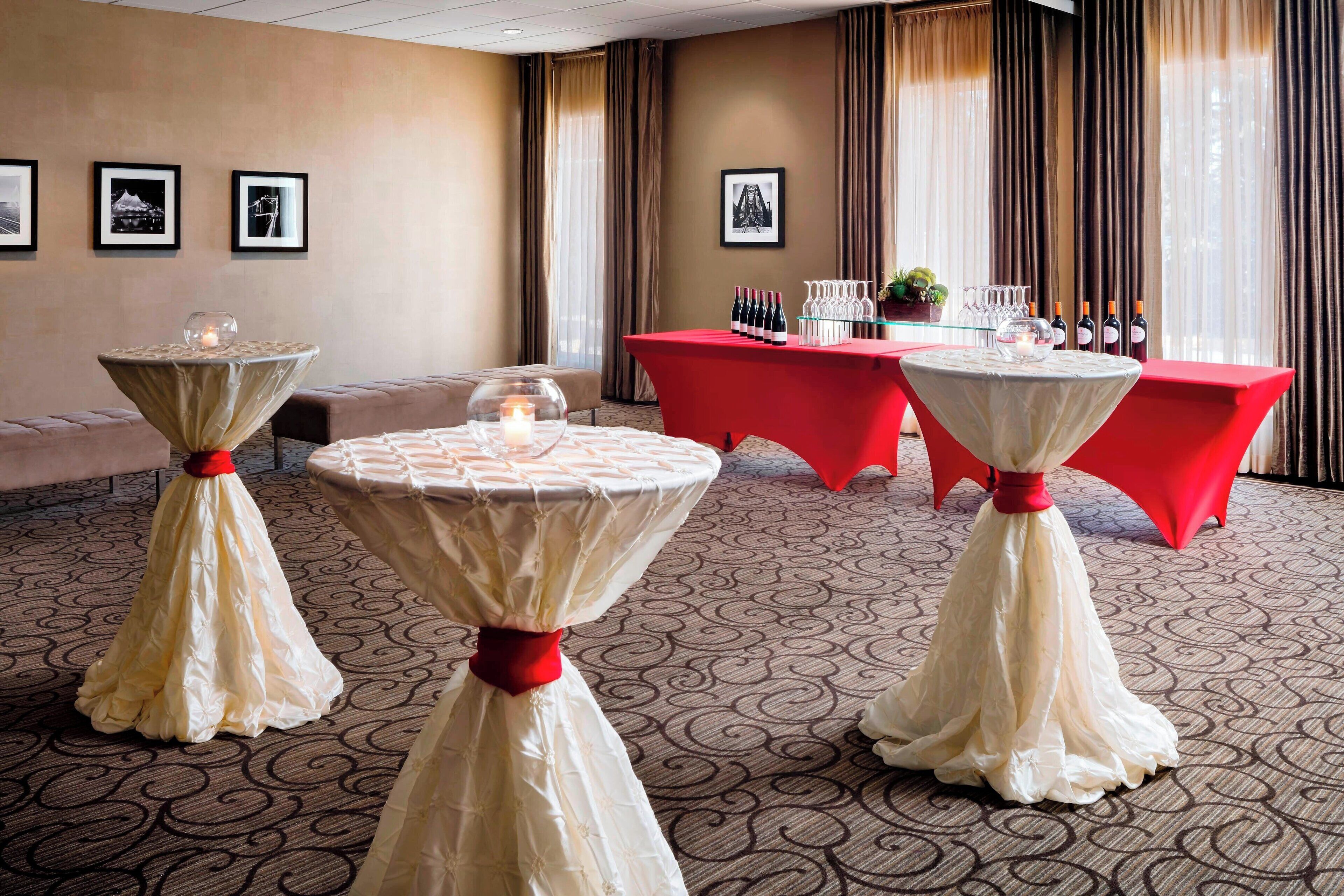 Habitación de hotel con una mesa roja dispuesta para comer, una mesa redonda con mantel blanco y un sofá color crema.