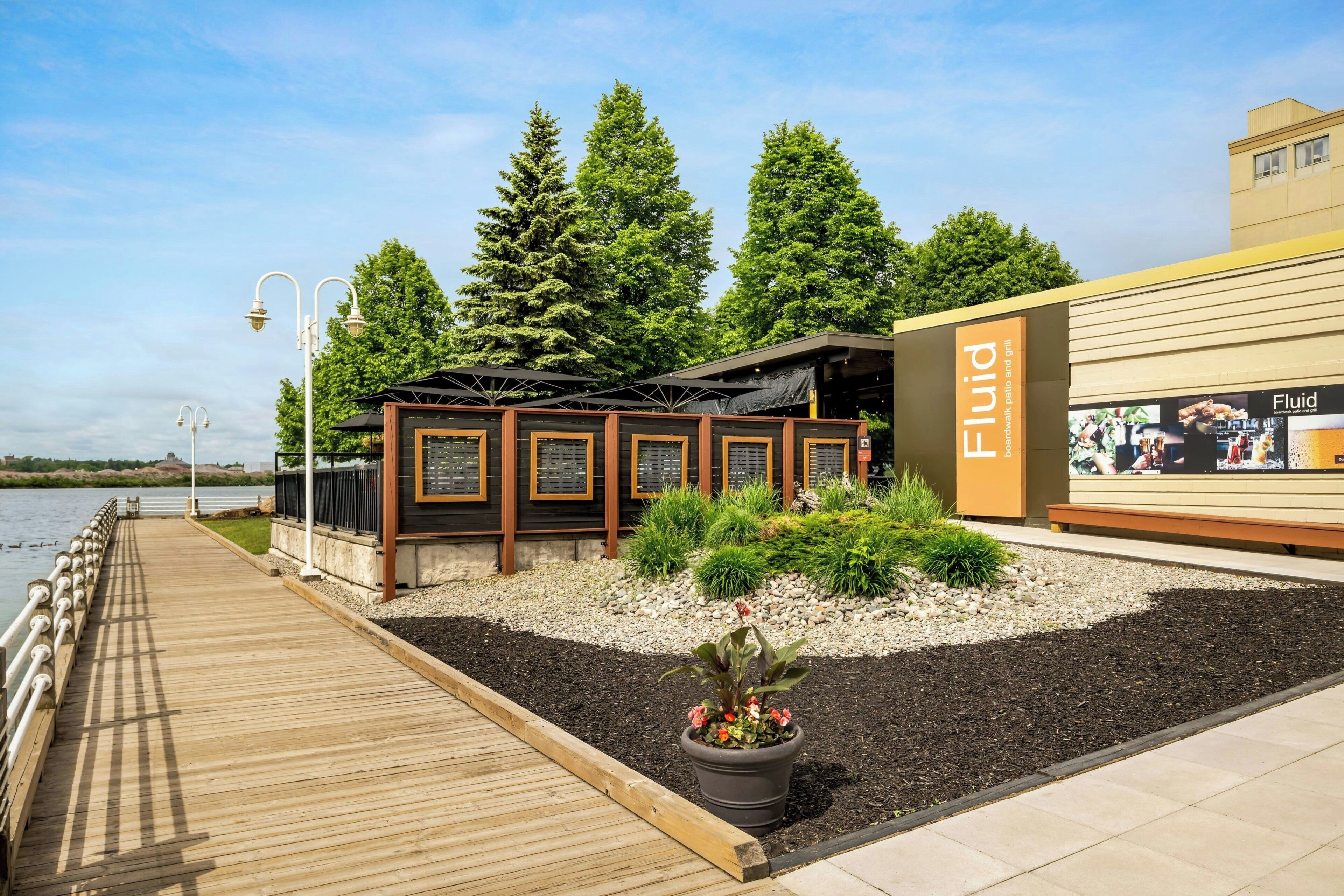 Un restaurant situé au bord de l’eau, avec une terrasse, une plateforme en bois et une vue sur l’eau.