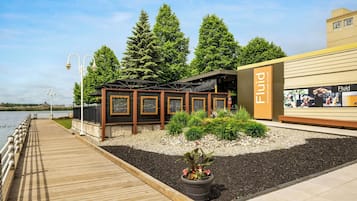 Un restaurant situé au bord de l’eau, avec une terrasse, une plateforme en bois et une vue sur l’eau.