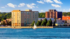 A waterfront cityscape with modern buildings, a sailboat, and a clear sky. - Delta Hotels by Marriott Sault Ste. Marie Waterfront (Sault Ste. Marie)