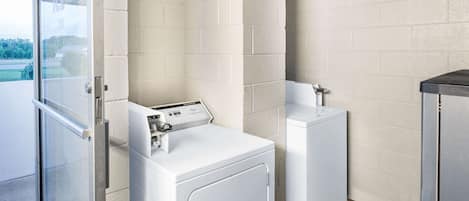 A laundry room with a front-loading washer and dryer, a sink, and a glass door leading to an outdoor area.