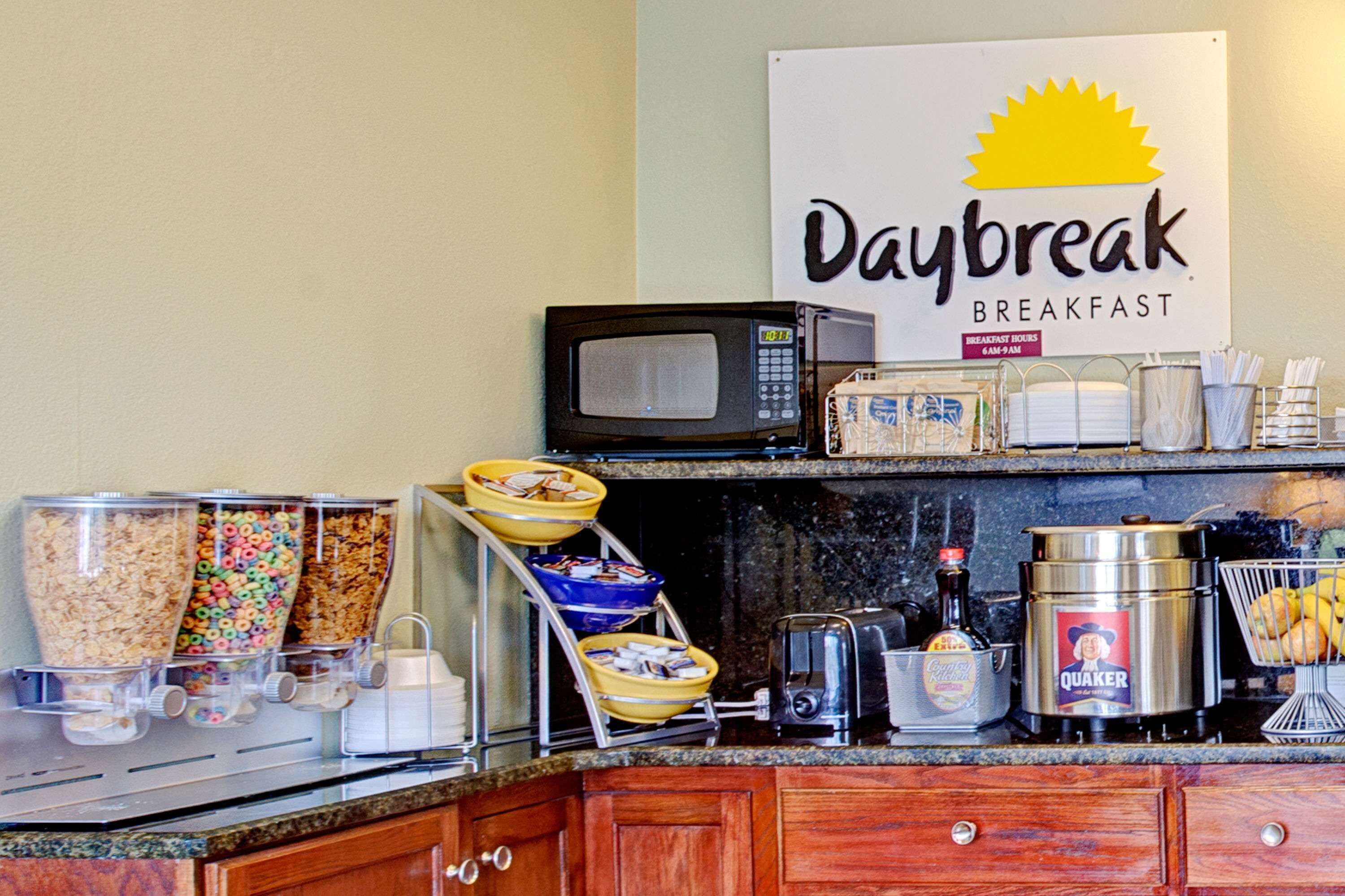 A breakfast buffet setup with cereal, fruits, and a coffee station.
