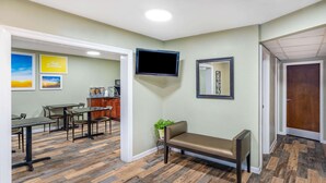 A room with a wooden herringbone floor, a bench, a television mounted on the wall, and a dining area with tables and chairs. - Days Inn by Wyndham Clarksville TN (Clarksville)