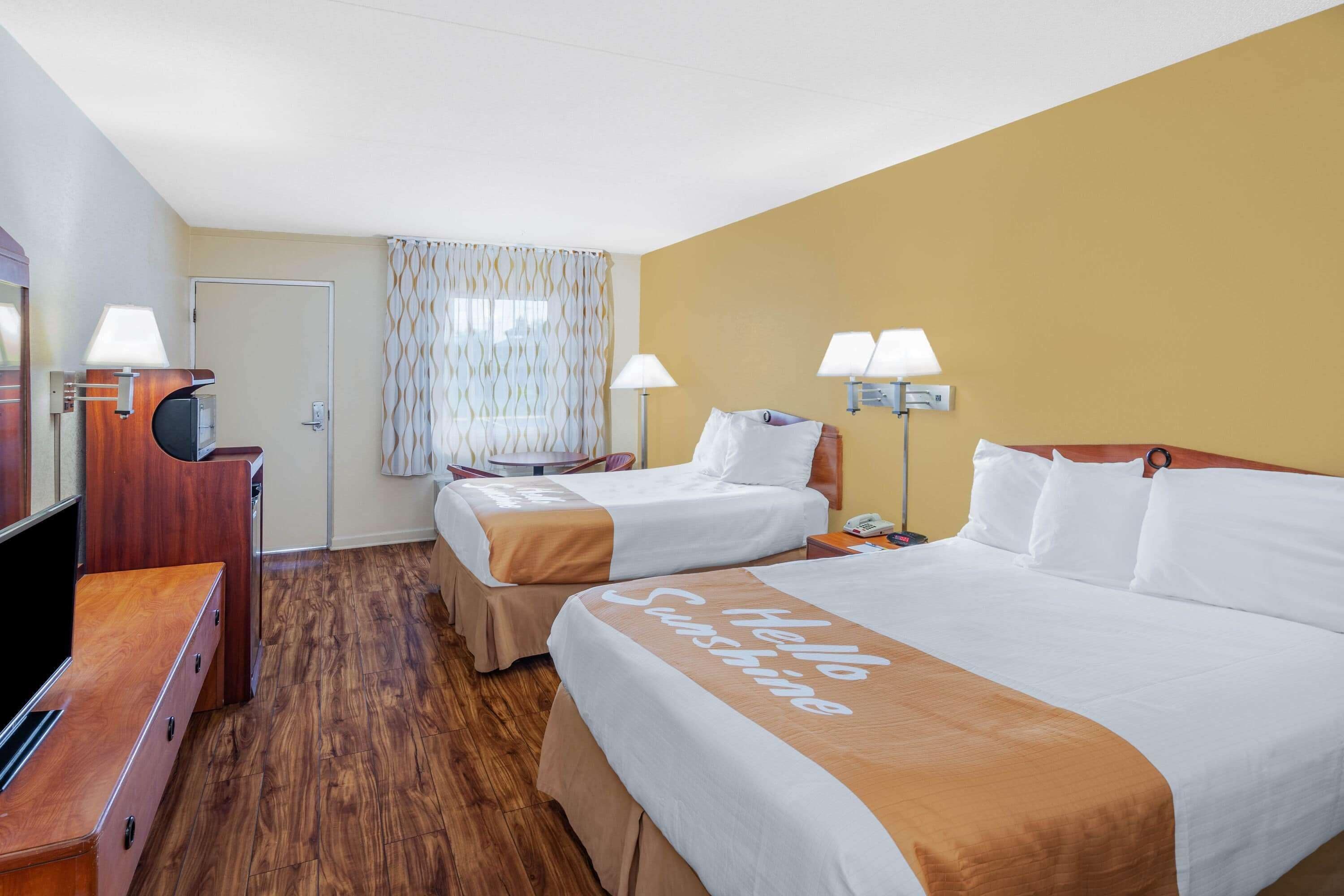 A hotel room with two beds, a TV, and a desk.
