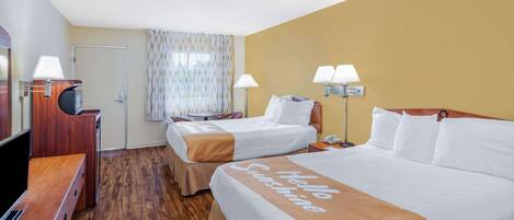 A hotel room with two beds, a TV, and a desk.