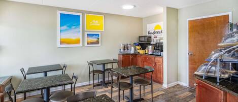 A breakfast area with tables and chairs, a coffee station, and a sign for Daybreak Breakfast.