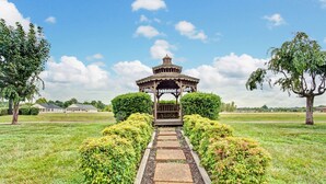 A gazebo with a wooden structure and a tiled roof, surrounded by a garden with a stone pathway leading to it. - Days Inn by Wyndham Clarksville TN (Clarksville)