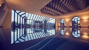Un interior moderno con techo de vidrio, diseño de pared geométrico y suelo reflectante.