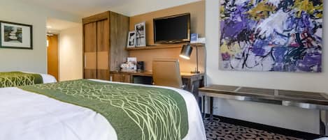 A hotel room with a bed, desk, chair, and a large abstract painting on the wall.