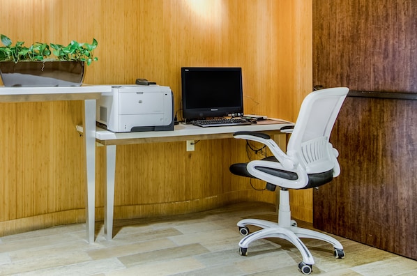 Un espace de travail équipé d’un ordinateur, d’une imprimante et d’un fauteuil de bureau blanc.