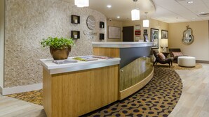 A reception area with a wooden reception desk, a potted plant, and a wall-mounted sign reading "Comfort Inn".