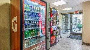 A vending machine area with Gatorade and Coca-Cola options, an exit sign, and a stone wall visible through the door.