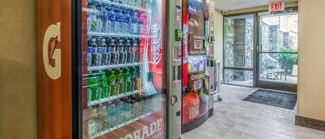 A vending machine area with Gatorade and Coca-Cola options, an exit sign, and a stone wall visible through the door.