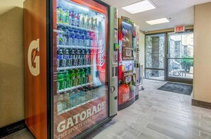 A vending machine area with Gatorade and Coca-Cola options, an exit sign, and a stone wall visible through the door. - Comfort Inn Raleigh Midtown (Raleigh)