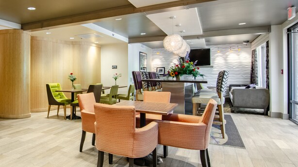 A modern dining area with a central table, surrounded by wicker chairs, and a seating area with a sofa and armchairs.