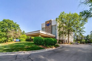 A Comfort Inn hotel with a modern design, featuring a stone facade and a covered parking area. - Comfort Inn Raleigh Midtown (Raleigh)