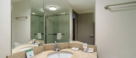 A modern bathroom with a large mirror, a sink, and a towel rack.