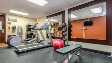 A gym with treadmills, a stationary bike, a bench, and exercise balls.