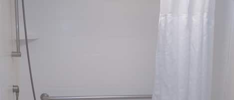 A white bathroom with a bathtub, a shower, and a grab bar.