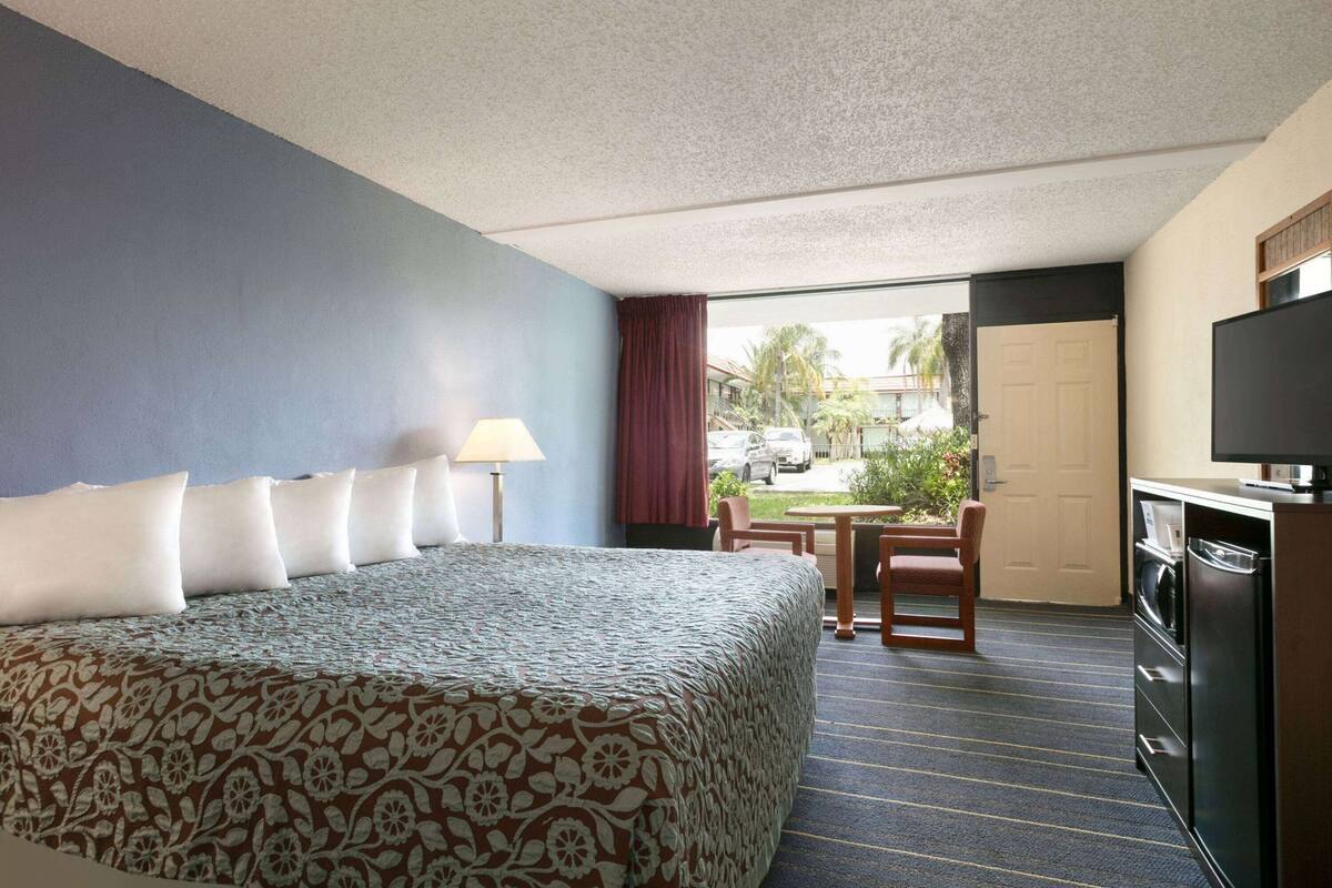 Ein Hotelzimmer mit Bett, Schreibtisch, Stuhl, Fernseher und Blick nach draußen.