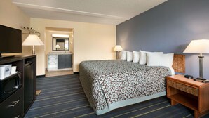 Una habitación de hotel con cama, lámparas de noche, televisor, escritorio y espejo.