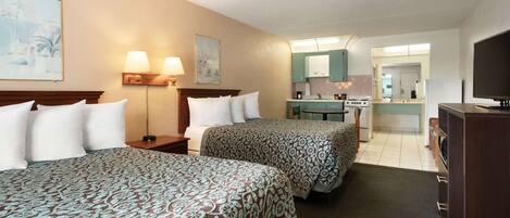 A hotel room with two beds, a desk, a chair, a TV, and a bathroom visible through an open door.