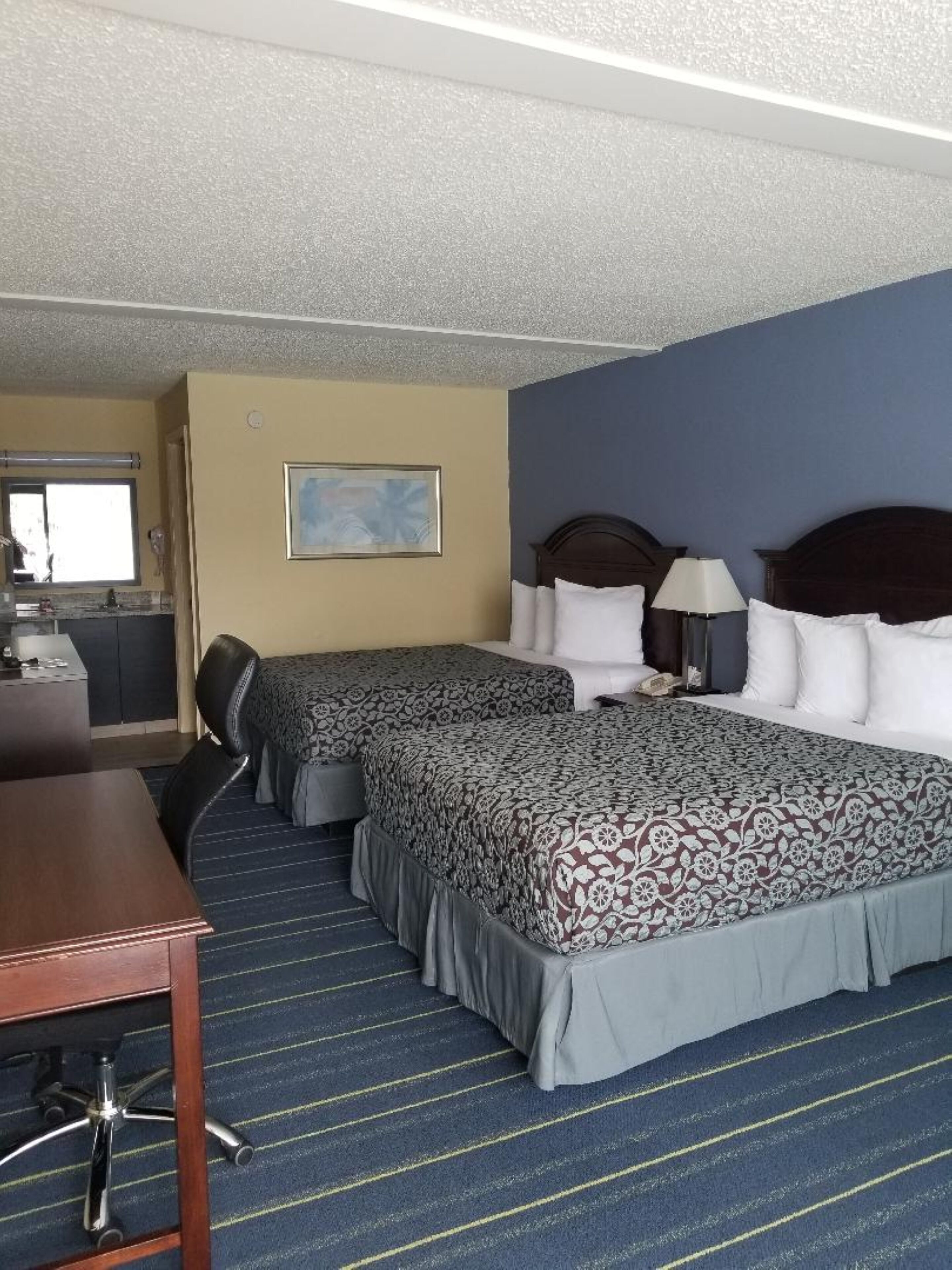 Een hotelkamer met twee bedden, een bureau en een stoel.