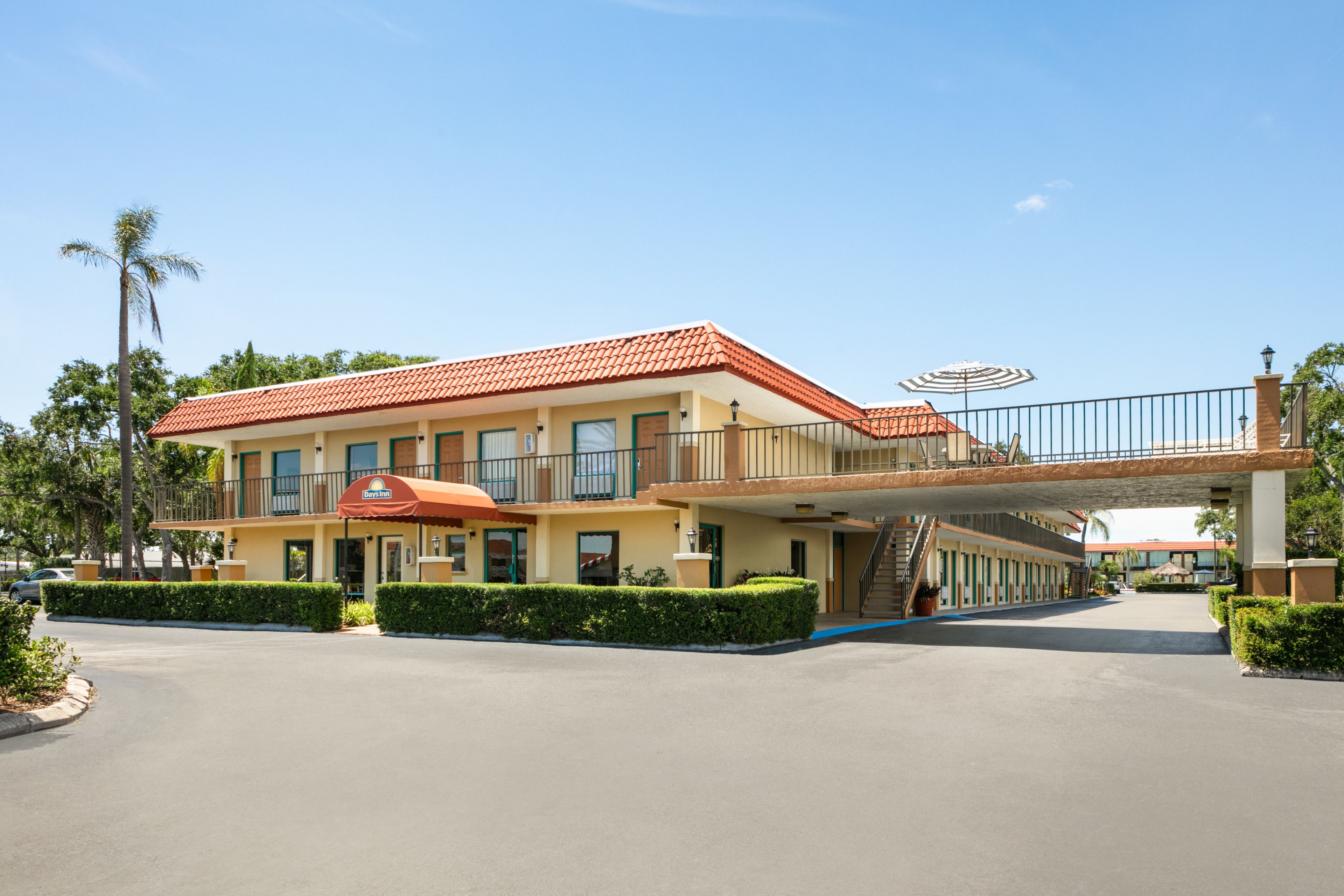 Un hotel con techo de tejas rojas, un acceso cubierto y un balcón.