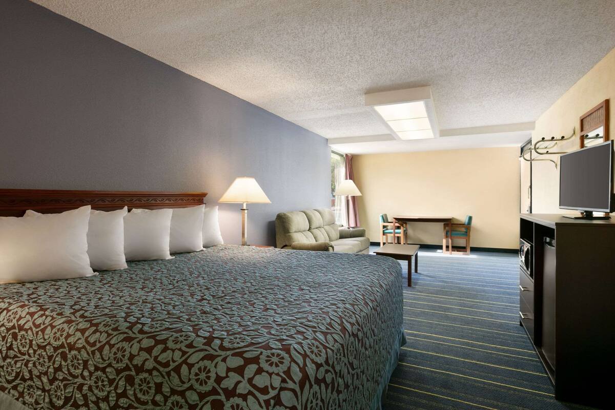 Ein Hotelzimmer mit einem großen Bett, einem Schreibtisch, einem Stuhl, einem Fernseher und einer Waschmaschine.