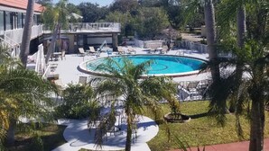 Un resort con piscina central rodeada de palmeras y sillas de descanso.