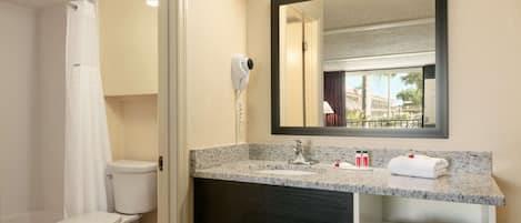 A bathroom with a toilet, sink, and mirror.