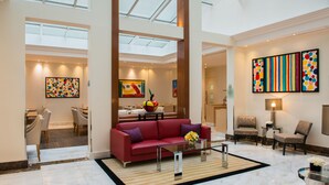 A spacious lobby with a red sofa, dining area, and artwork on the walls. - Atlantic Hotel (Paris)