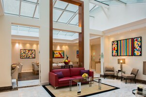 A spacious lobby with a red sofa, dining area, and artwork on the walls.