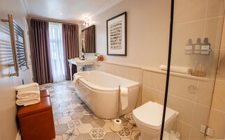 A bathroom with a bathtub, toilet, and shower area.