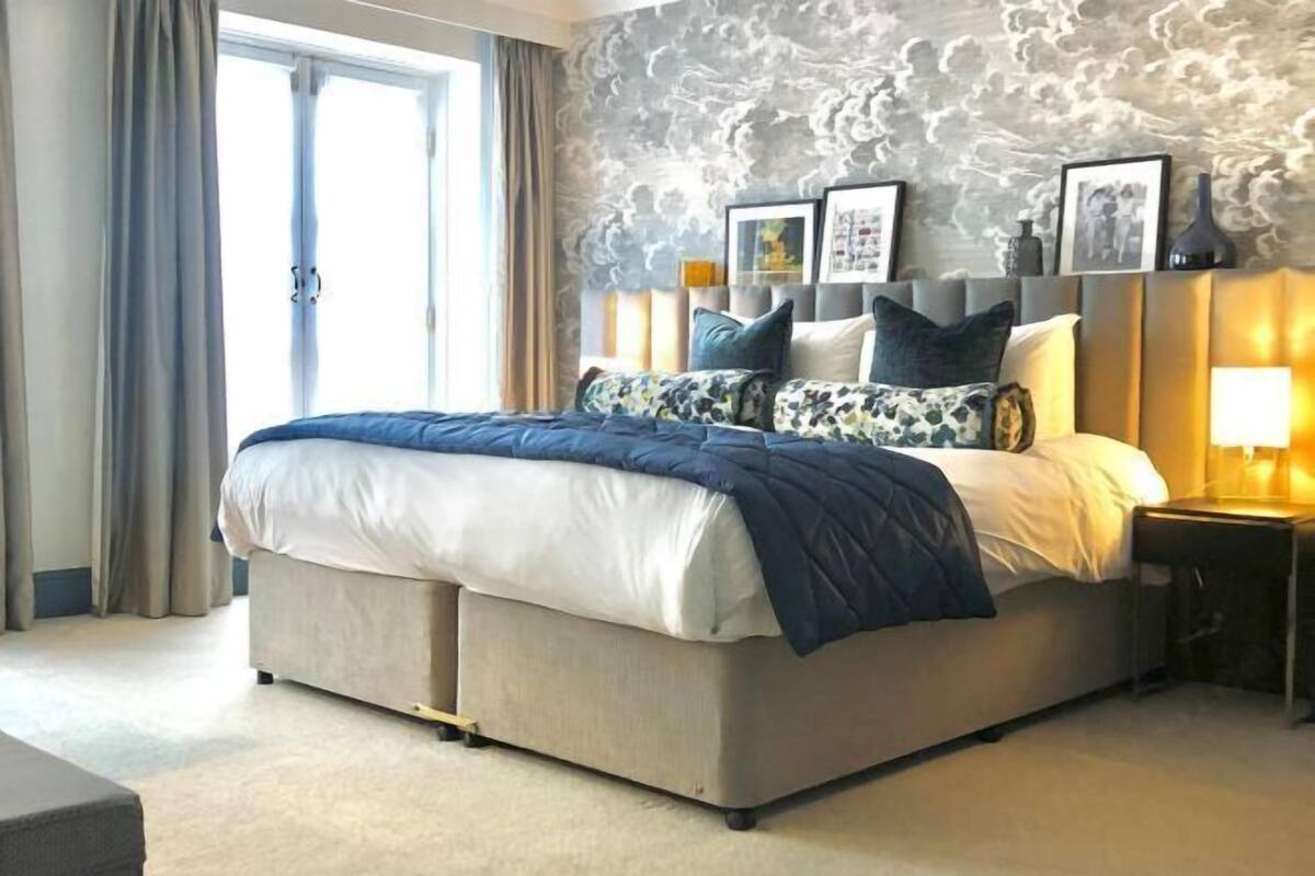 A bedroom with a bed, a nightstand, a lamp, and a window with curtains.