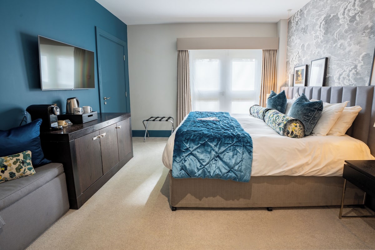 A hotel room with a bed, a desk, a chair, a TV, and a window.
