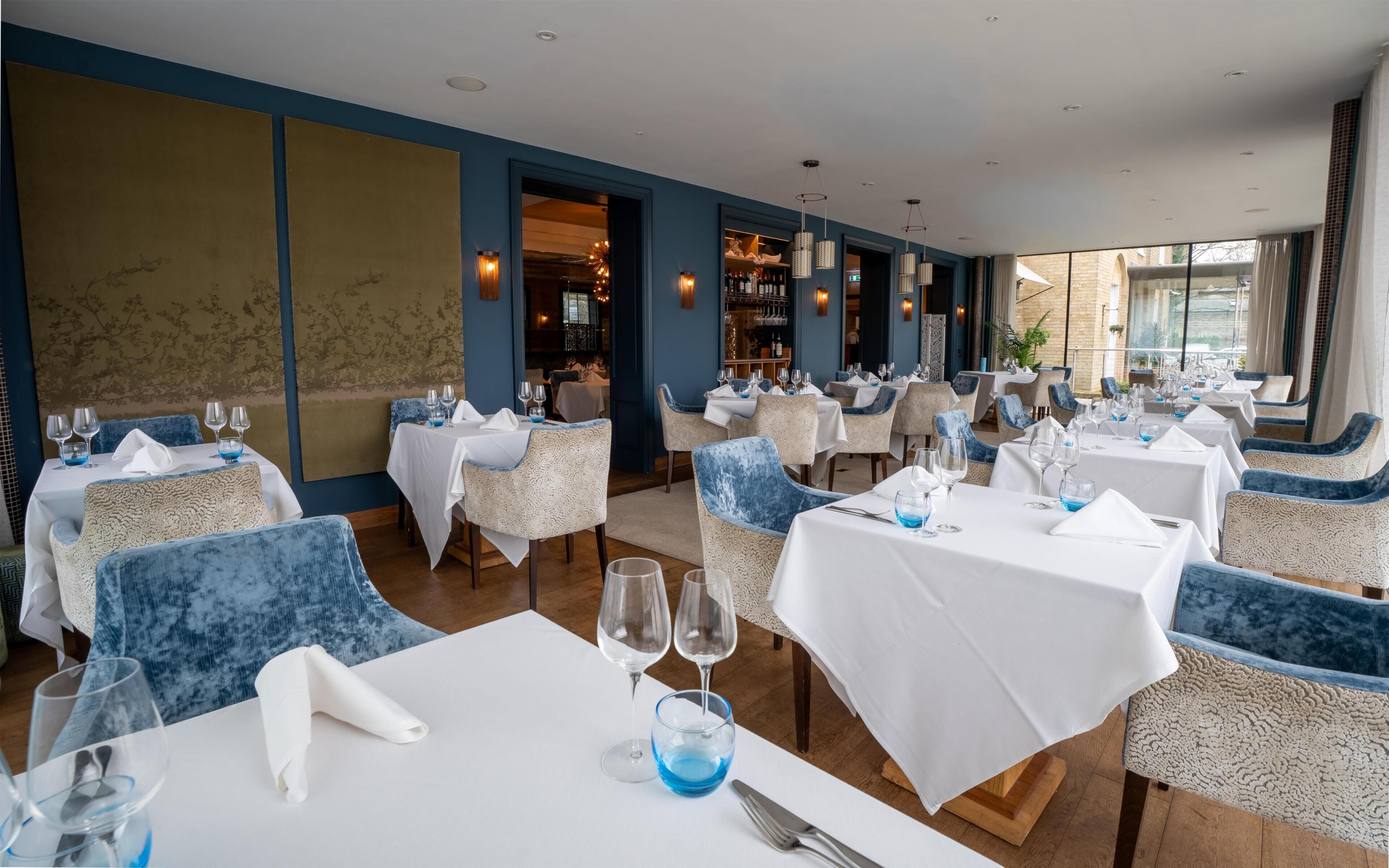 A restaurant with multiple tables, each set with wine glasses, napkins, and cutlery.