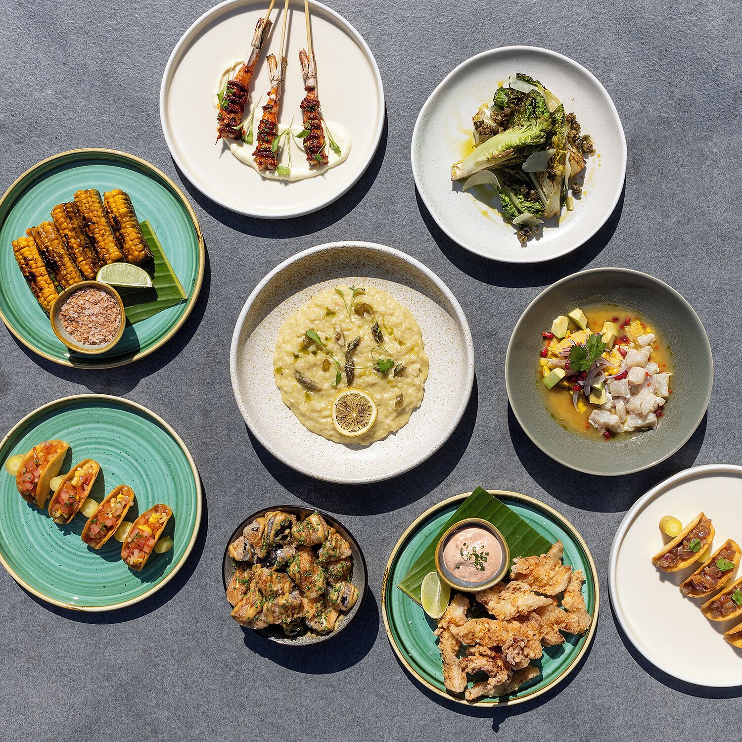 A variety of dishes on different plates, including grilled meat, corn, and seafood.