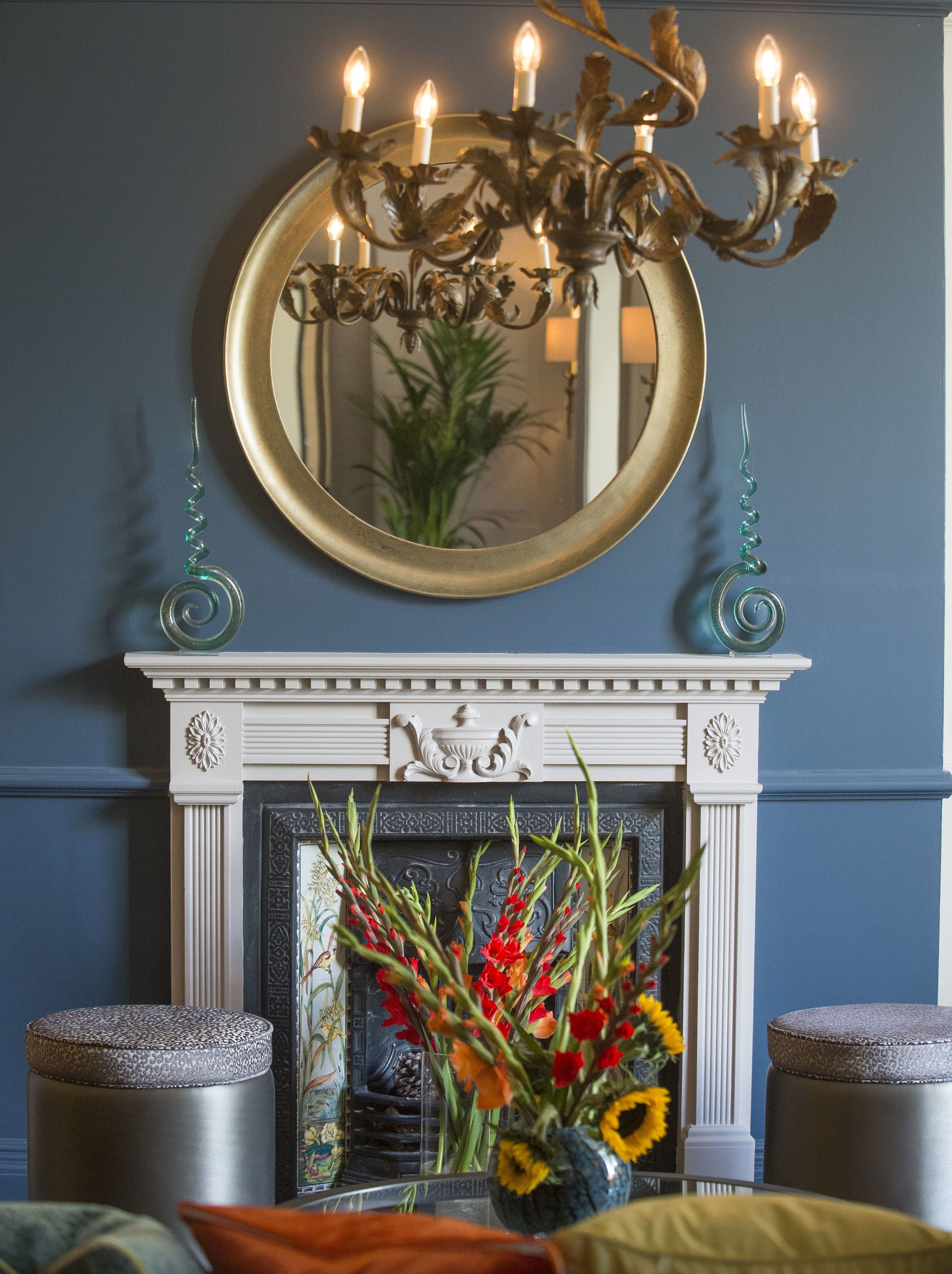 A room with a fireplace, a mirror, and a vase of flowers.