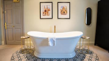 A bathroom with a freestanding bathtub, two framed pictures on the wall, and a door.