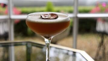 Un verre à cocktail, agrémenté d’une garniture, posé sur une serviette noire, lui-même placé sur une surface réfléchissante.