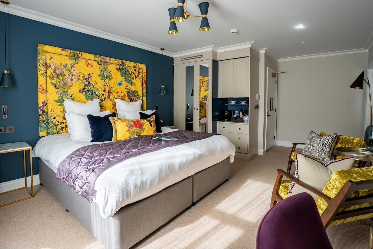 A bedroom with a large bed, bedside tables, a wardrobe, a desk, and a chair.