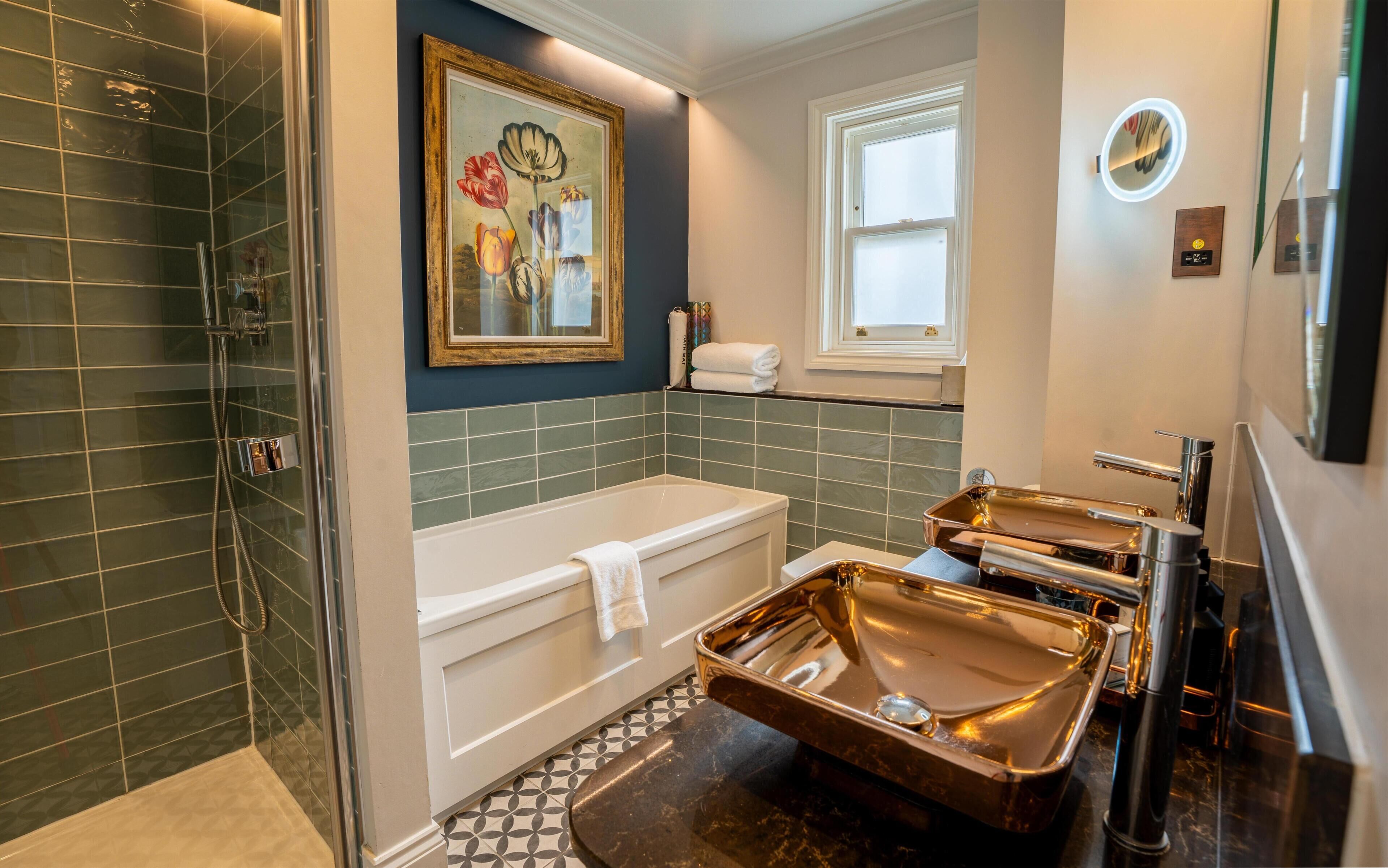 A modern bathroom with a bathtub, a shower, and a vanity with a large mirror.