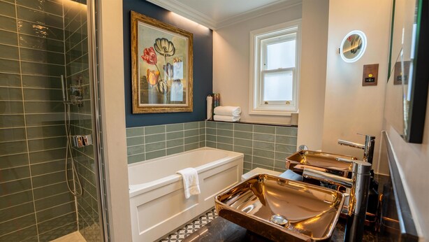 A modern bathroom with a bathtub, a shower, and a vanity with a large mirror. - The Gonville Hotel, a member of Radisson Individuals (Cambridge)